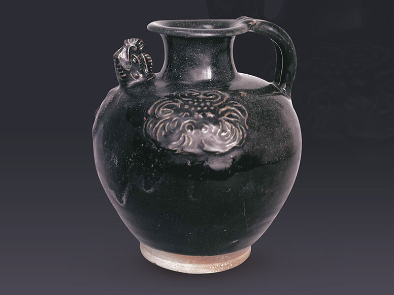 唐代．黑釉貼花執壺+執壺表面貼花并施黑釉，貼花突棱處因流釉而呈褐色，是結合二種裝飾技法的產物。（圖一）+圖片來源：《中國出土瓷器全集15陜西》，頁87。